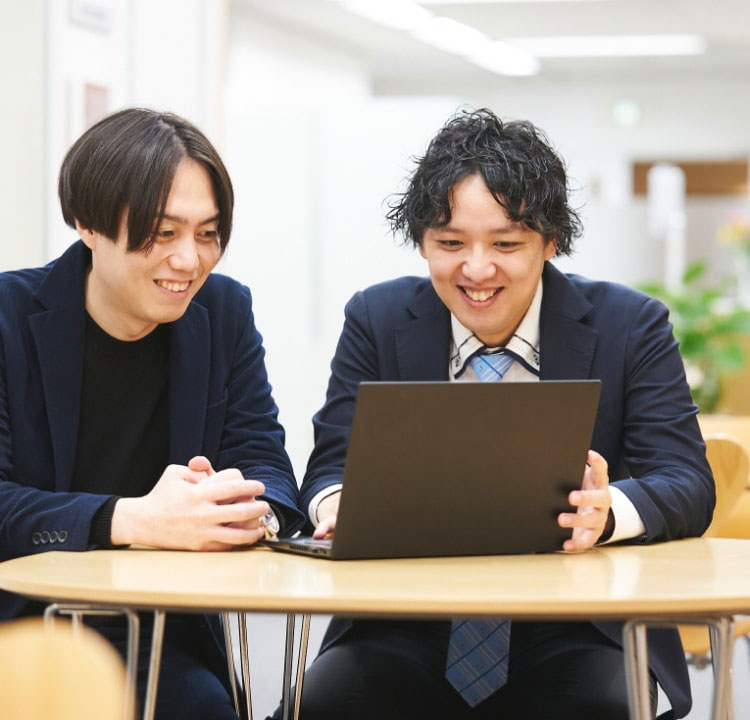 パソコンを見ながら笑う男性二人組