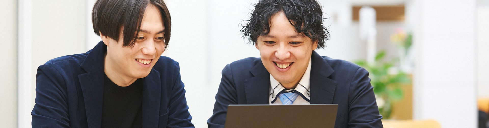 パソコンを見ながら笑う男性二人組